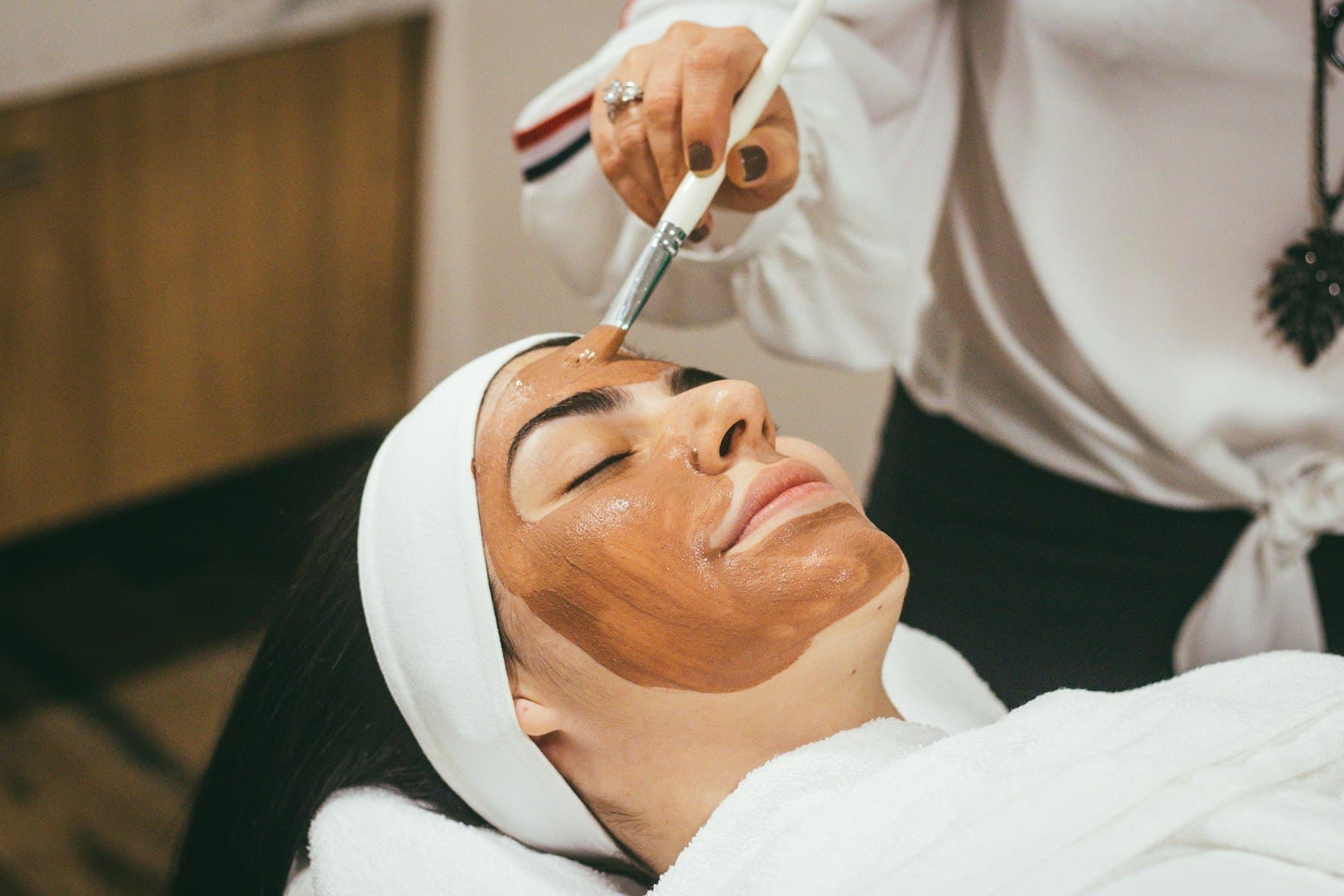 Person relaxing while a face pack is applied with a brush