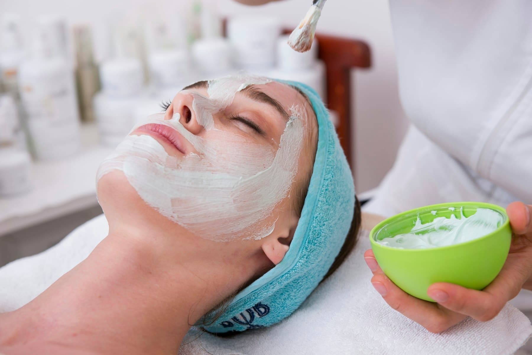 Woman with a cream face mask and headband during a facial