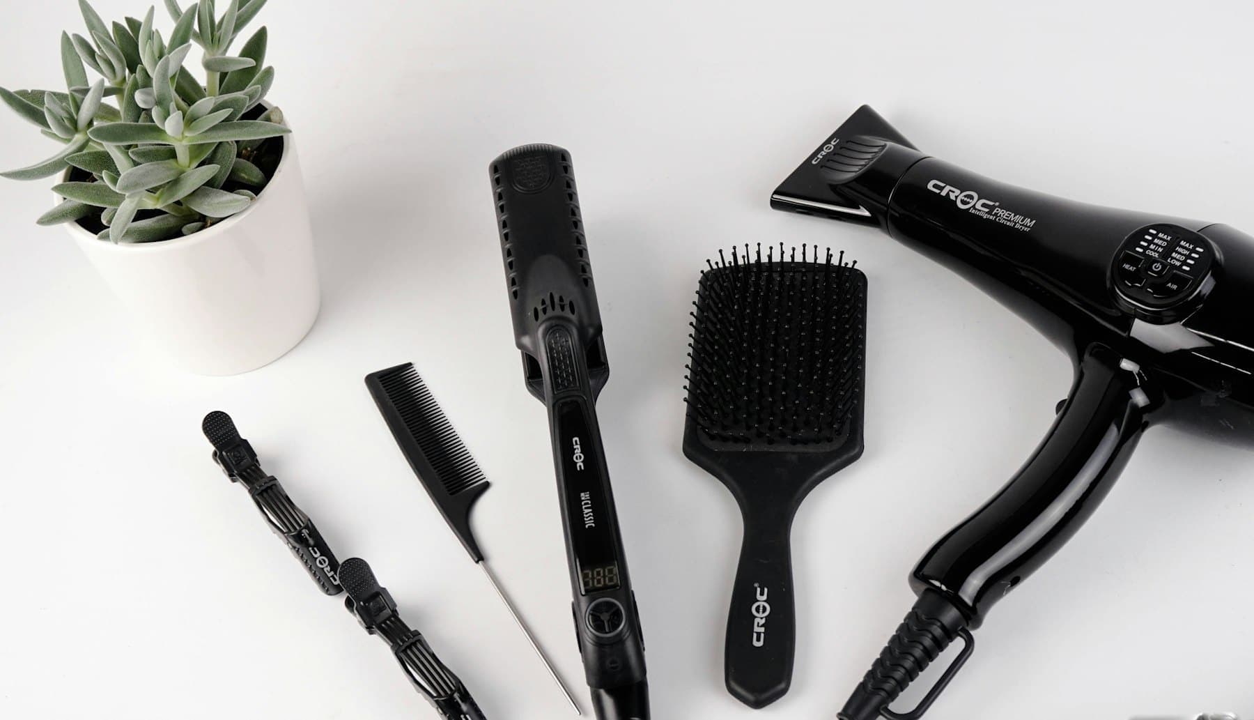 Hairdryer, brushes and sectioning clips arranged on a white surface