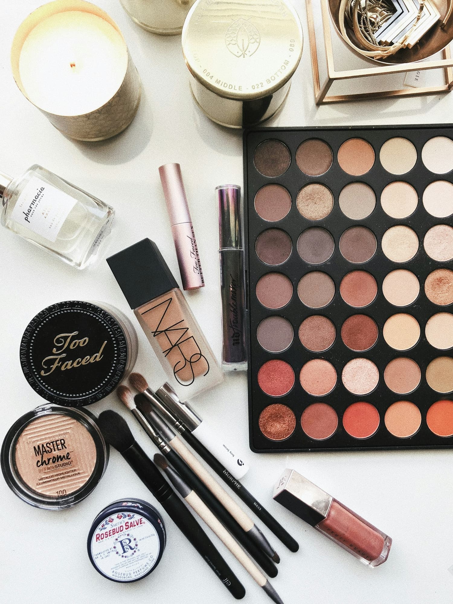 Eyeshadow palette, foundation and brushes laid out on white