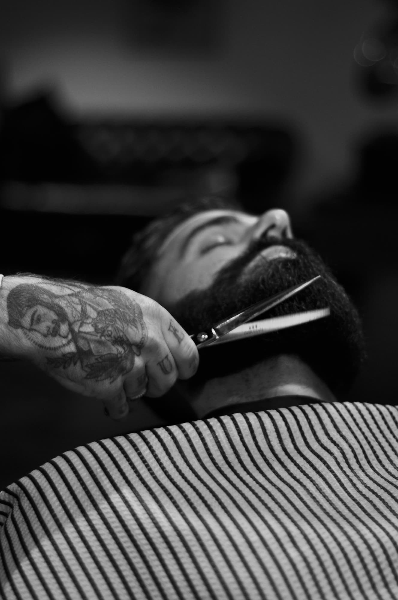 Black and white close-up of a beard being trimmed with scissors