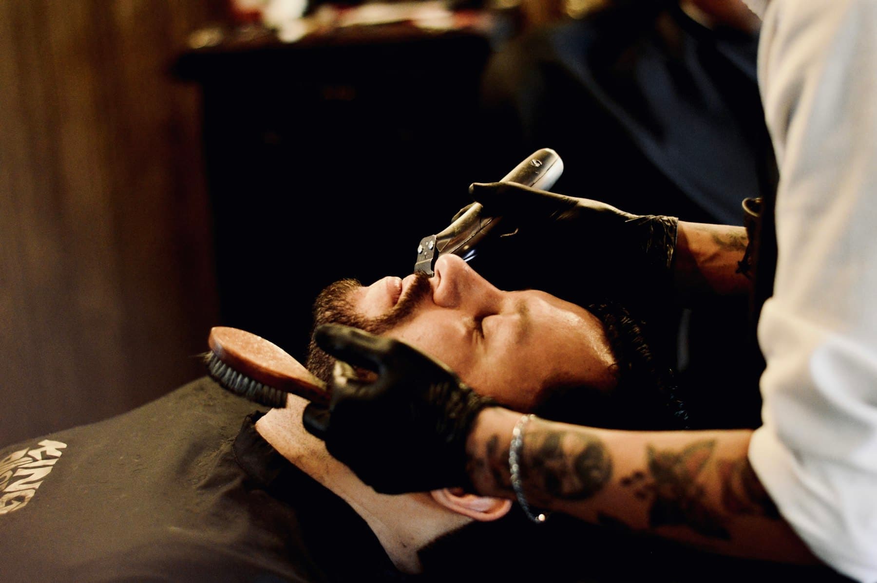 Man reclining while a groomer attends to his face