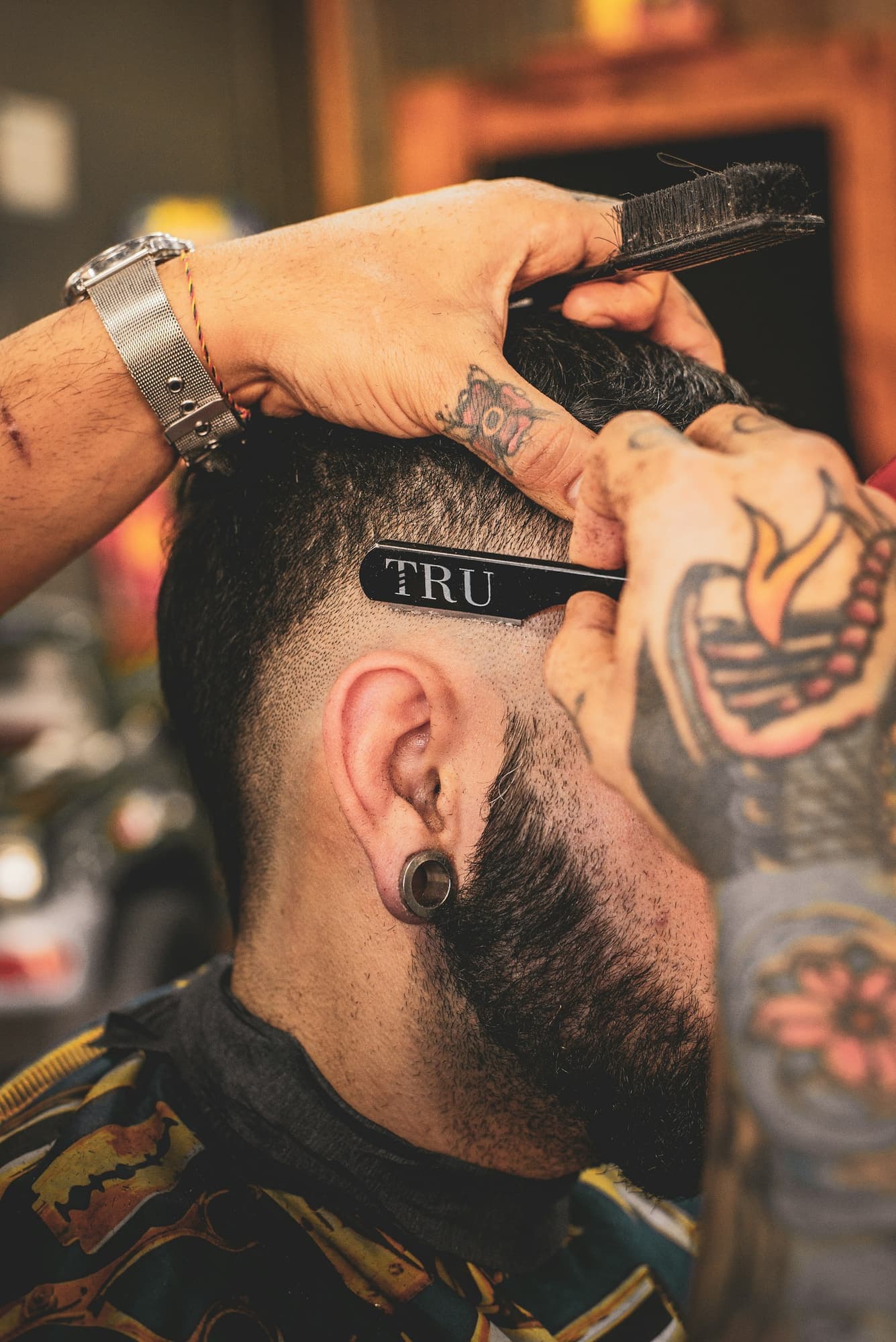Close-up of a barber shaping the sides of a man's haircut