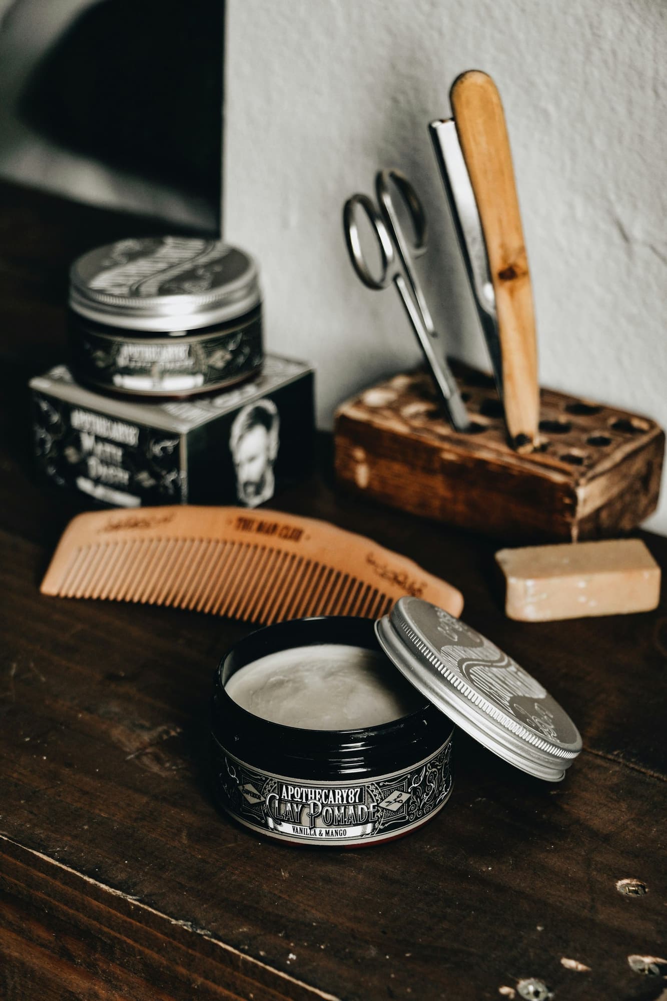 Vintage grooming tin, wooden comb, scissors and razor on a shelf