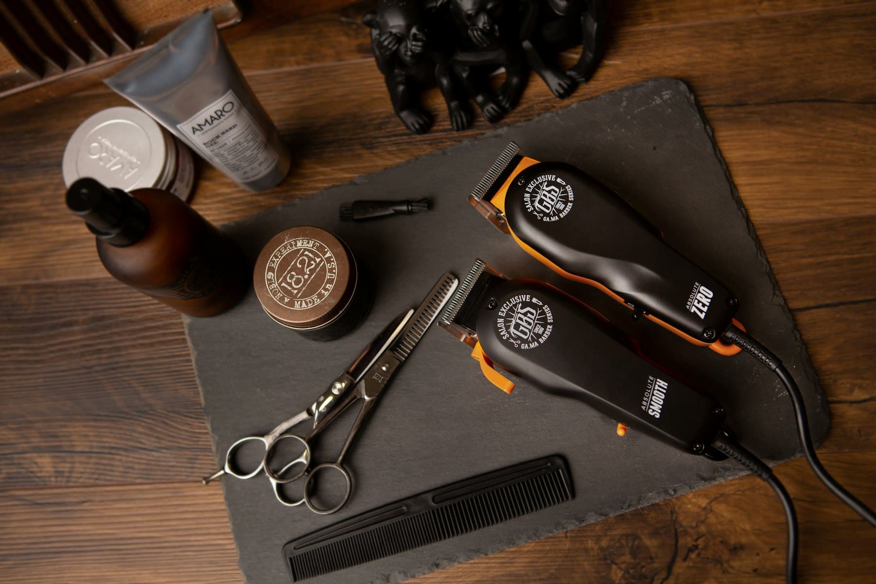 Hair clippers, scissors, comb and grooming products on a dark wooden surface