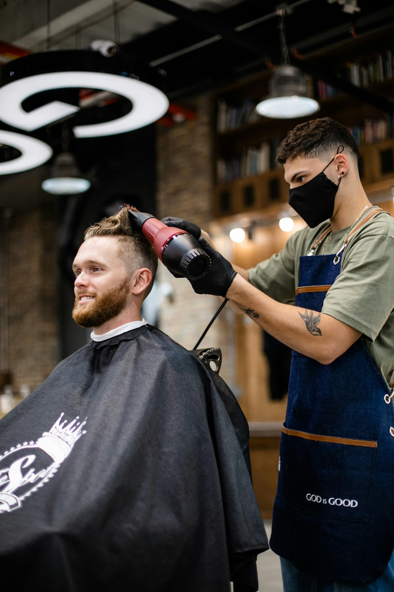 Barber blow-drying a client's hair in a busy barbershop