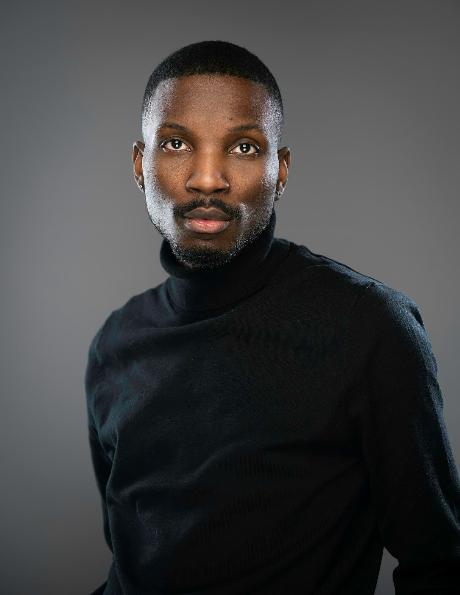 Studio portrait of a man in a black turtleneck against a grey background