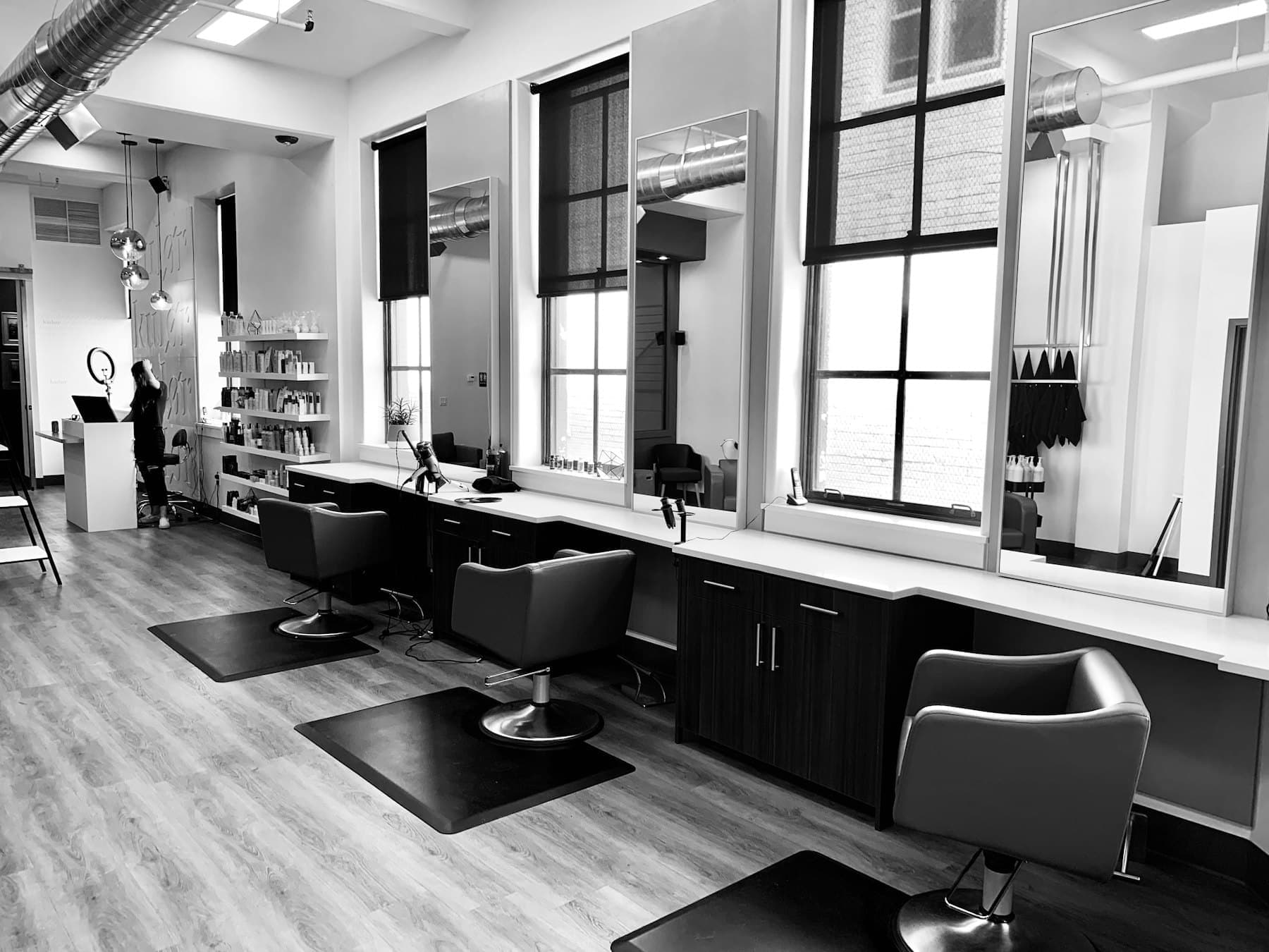 Black and white photograph of a spacious salon with a row of styling chairs