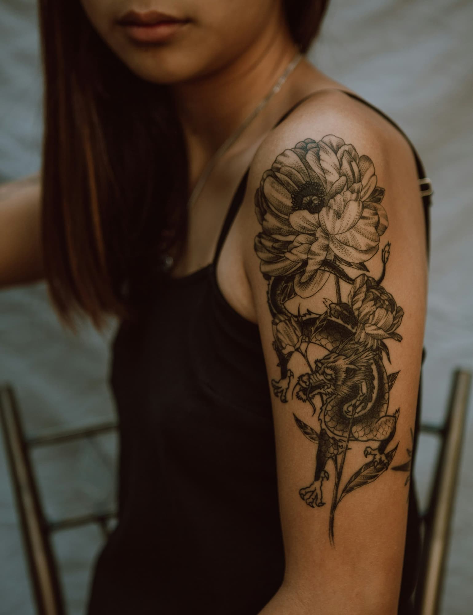 Detailed floral line-work tattoo on a woman's upper arm