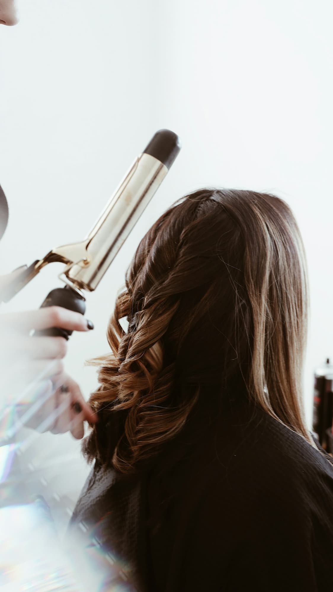 Long brown hair being curled with a curling iron