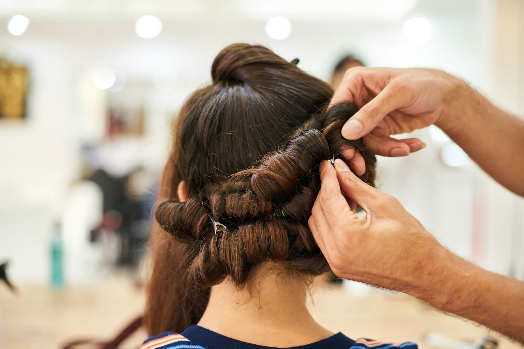 Stylist pinning a woman's hair into a structured updo